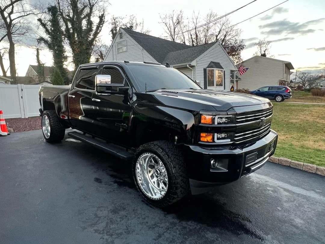 Detailed lifted black Chevy Silverado truck in driveway